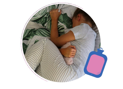 A young person suffering from period pain using a hot water bottle