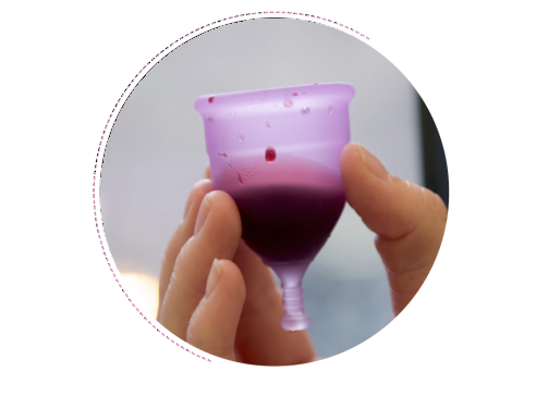 A hand holds a menstrual cup that is filled with blood